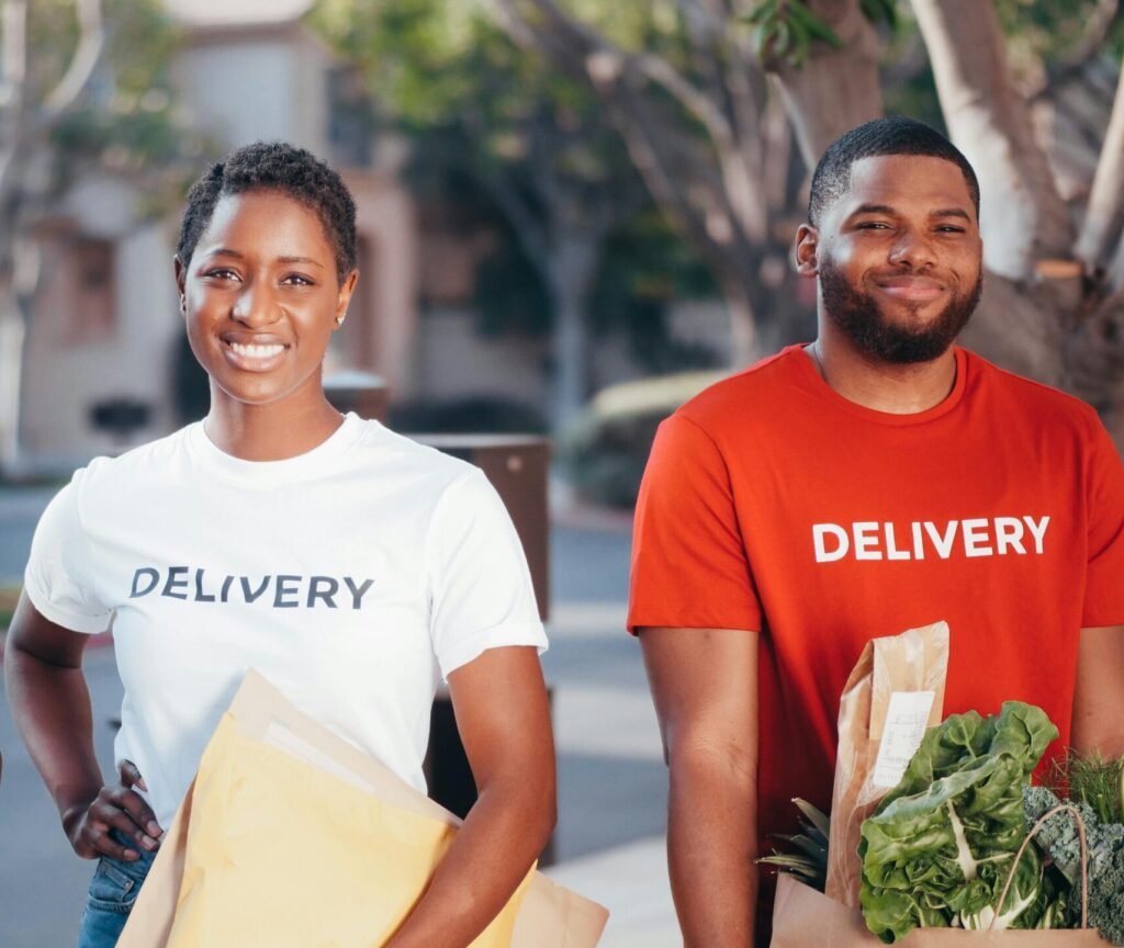 Three delivery team members holding packages with smiles outdoors, showcasing teamwork and service.